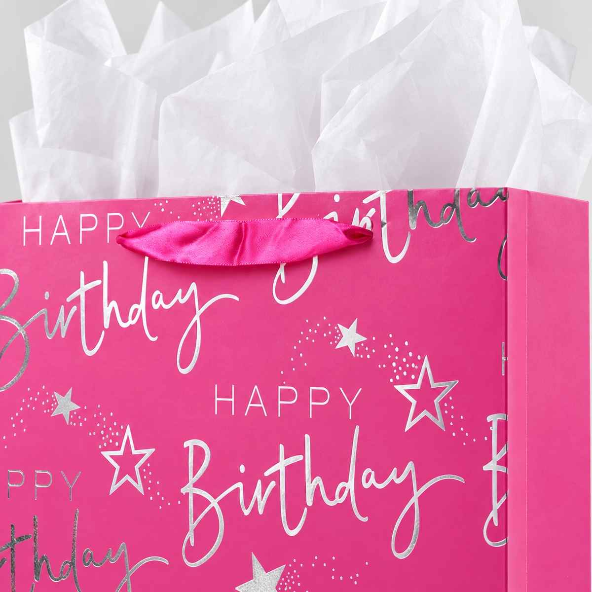 Close-up of the pink satin handle, silver birthday lettering and stars, and white tissue.