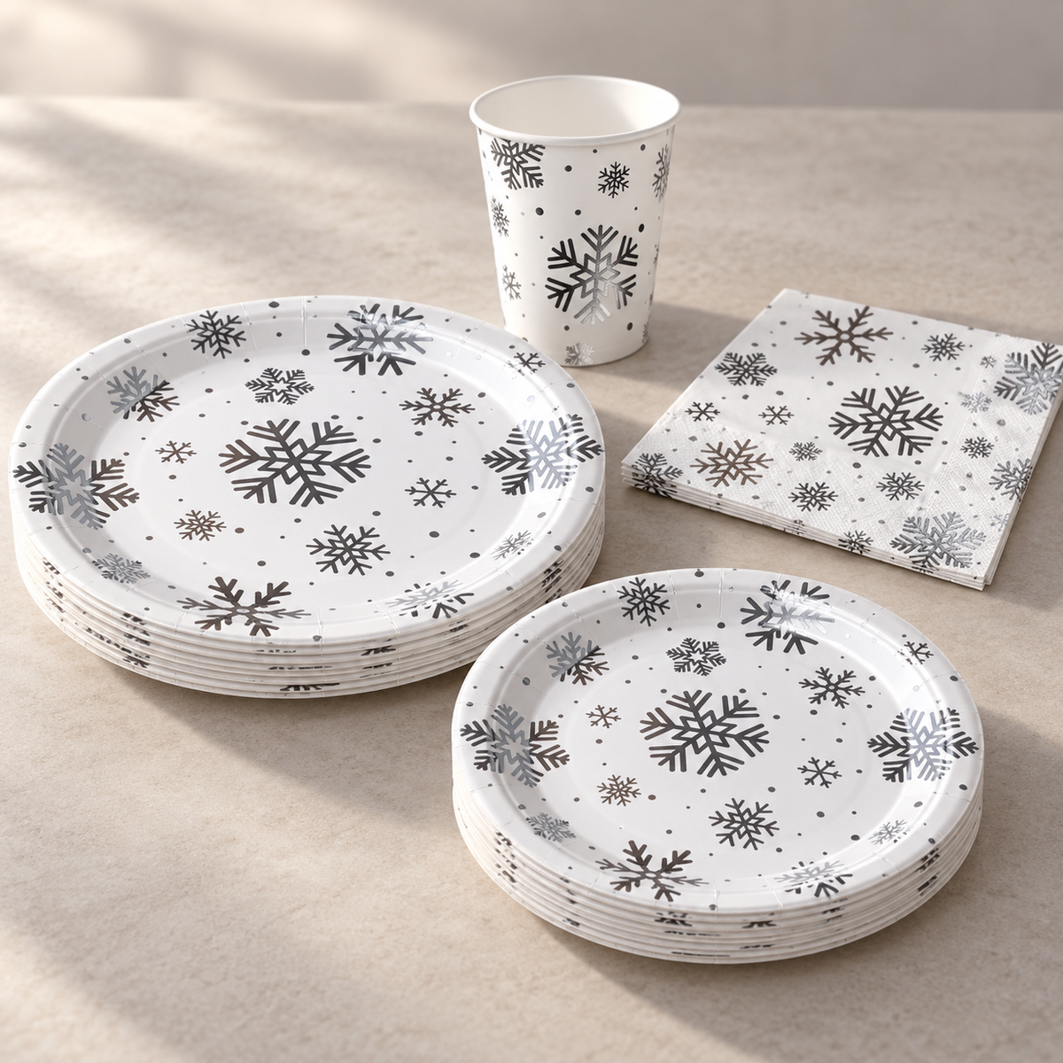 Oblique profile of short stacks of the two silver snowflake paper plate sizes, with matching cup and napkin. Sample arrangement.