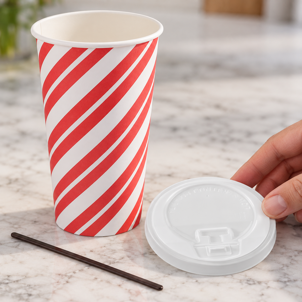 Close detail of a striped cup, matching white lid and dark stirrer.