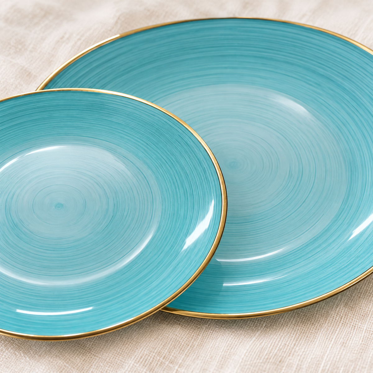 Close-up of aqua plastic plates showing fine concentric surface lines and thin gold rims. Flowers, flatware, tumblers and linen are styling props, not included.