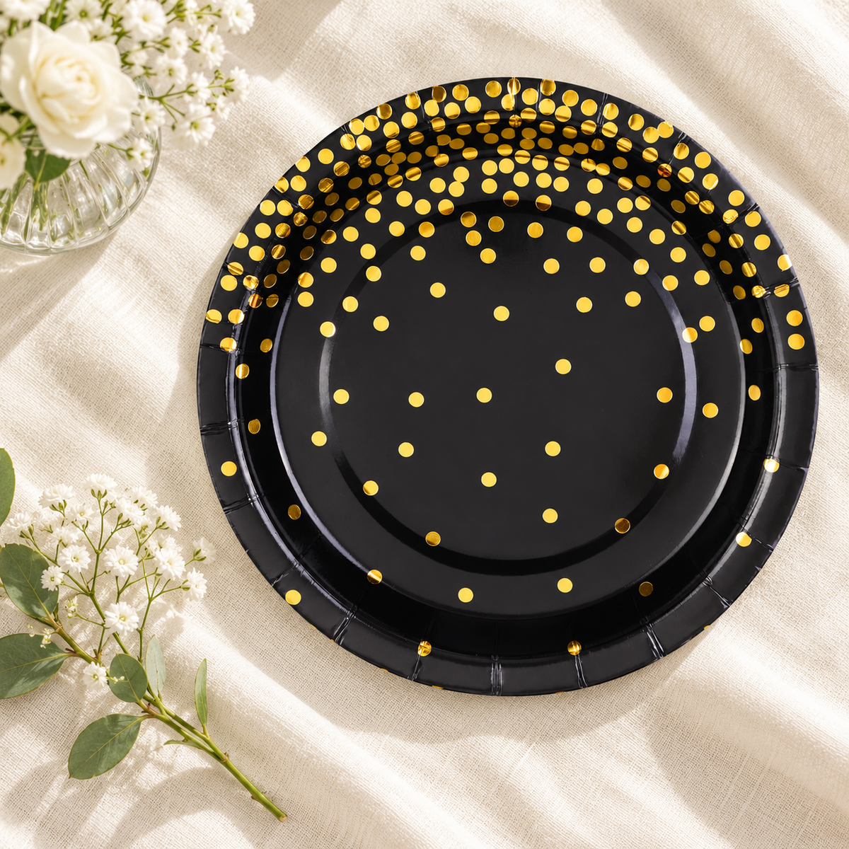 Overhead view of black paper plates showing the gold dot pattern. Food, tableware and decor are styling props, not included.