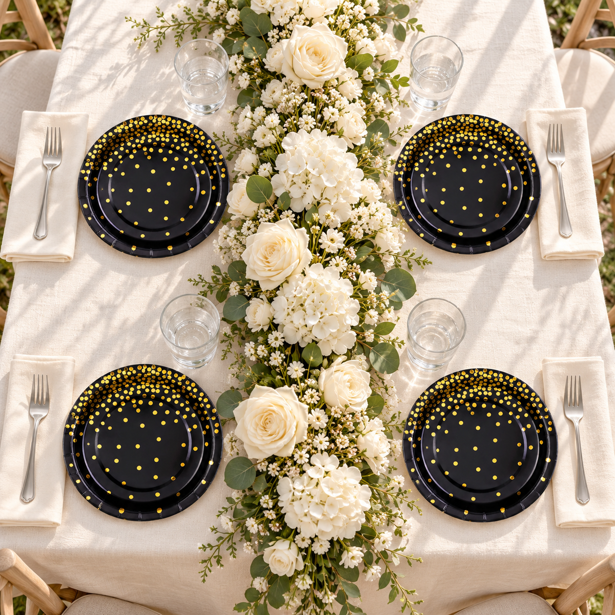 Overhead view of a four-guest table with black and gold dot paper plates. Food, tableware and decor are styling props, not included.