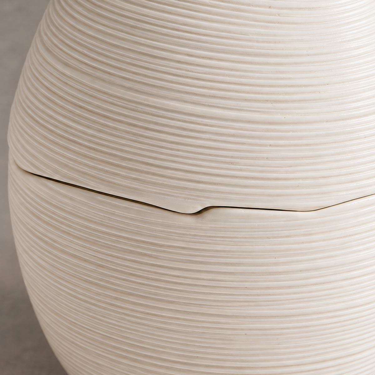 Macro of the egg-shaped ceramic bowl's fine horizontal ridges and fitted lid seam