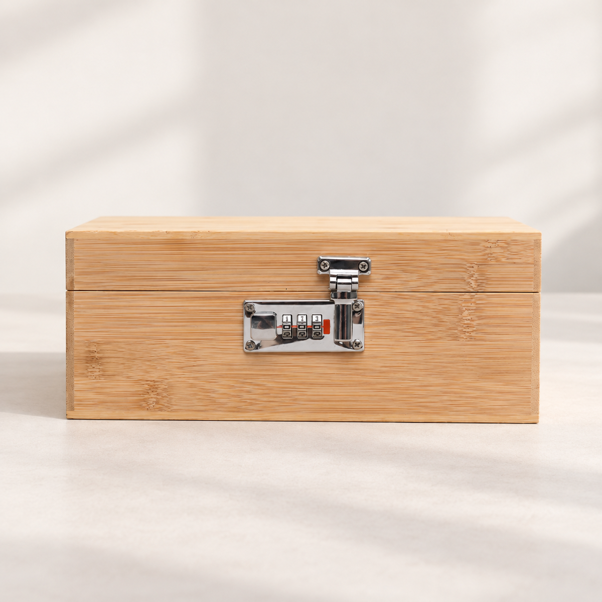 Closed wood clamshell storage box with a silver three-wheel latch on a pale tabletop.