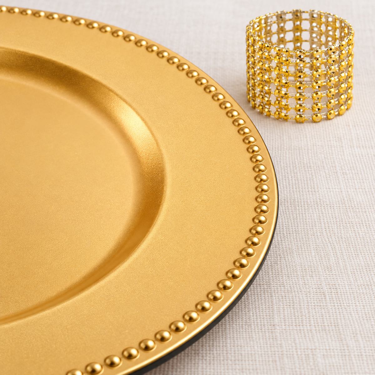 Close-up of gold beaded chargers and open-mesh napkin rings. Dinner plates, napkins, food and extra decor are styling props, not included.