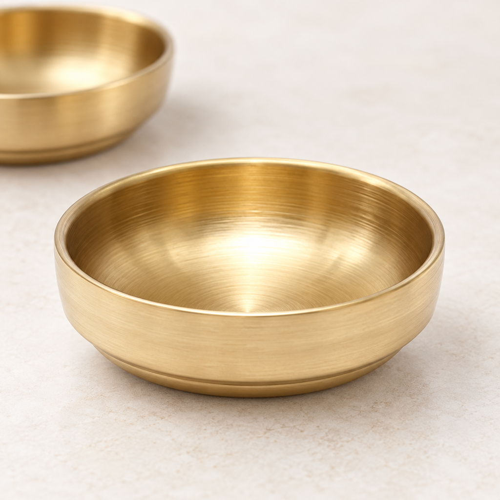 Close-up of gold stainless steel sauce dishes showing their brushed finish. Food and extra styling accessories are not included.