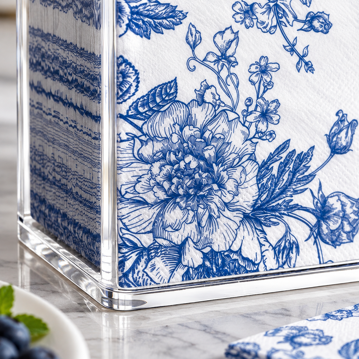 Close-up of the acrylic napkin holder's front corner and lower edge; napkins not included.