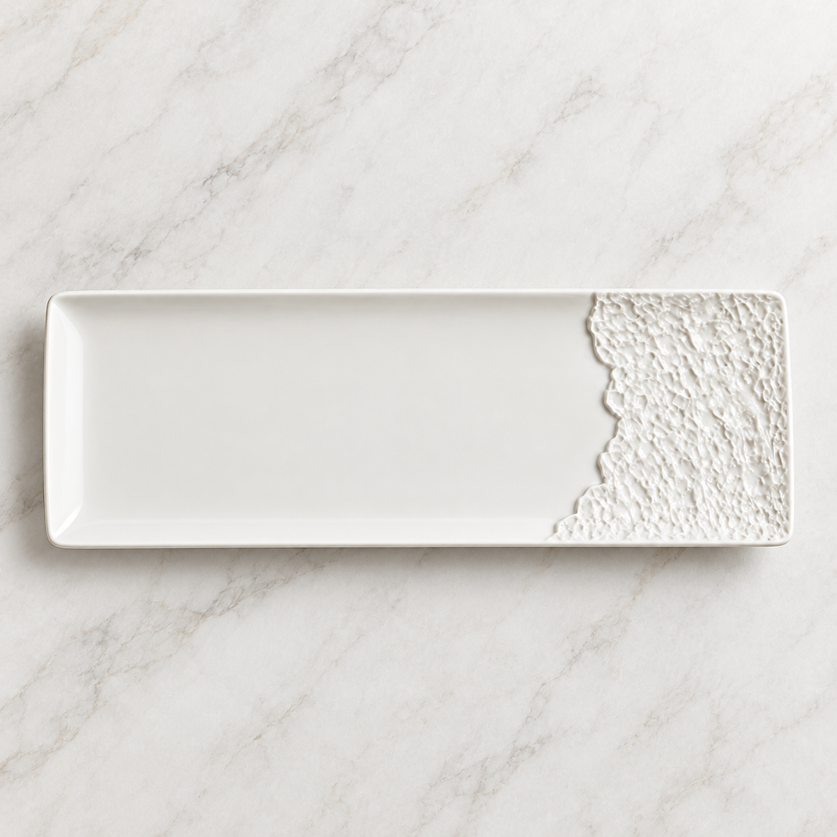 Overhead view of an empty rectangular porcelain platter with one rock-texture end.