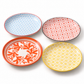 The four 7-inch Japanese-style ceramic plates on white, with blue, red, yellow and orange patterns and their original rim colors.