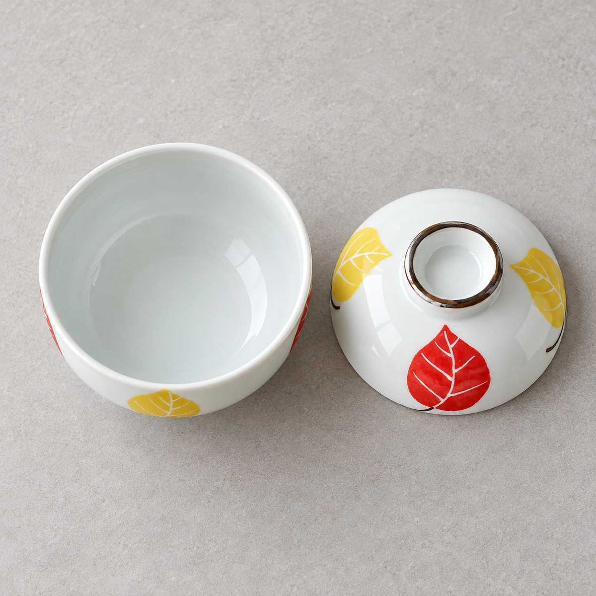 Overhead view of an empty leaf-pattern ceramic bowl and separate matching lid