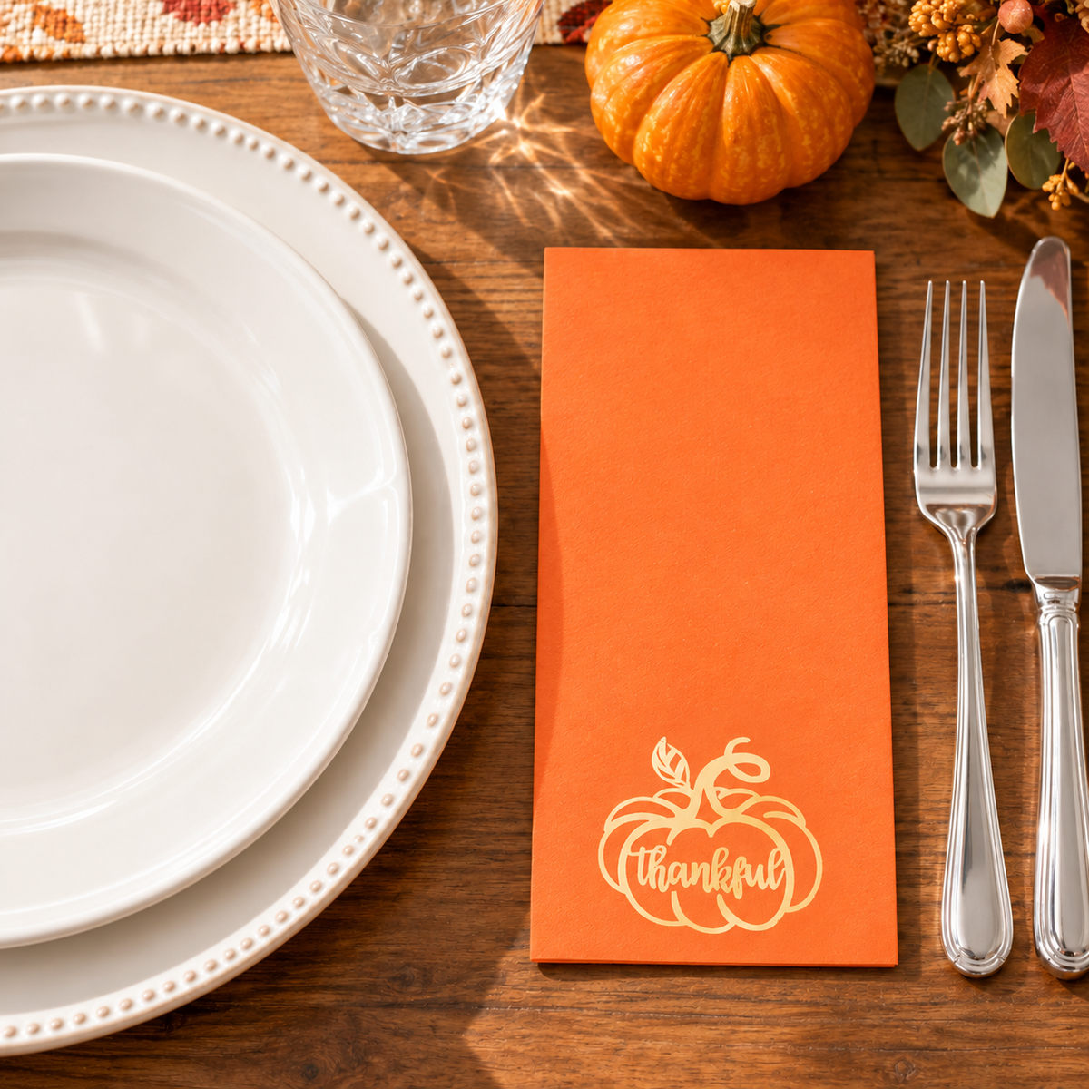 Thin folded orange paper napkins with gold pumpkin and Thankful print. Food, tableware and decor are styling props, not included.