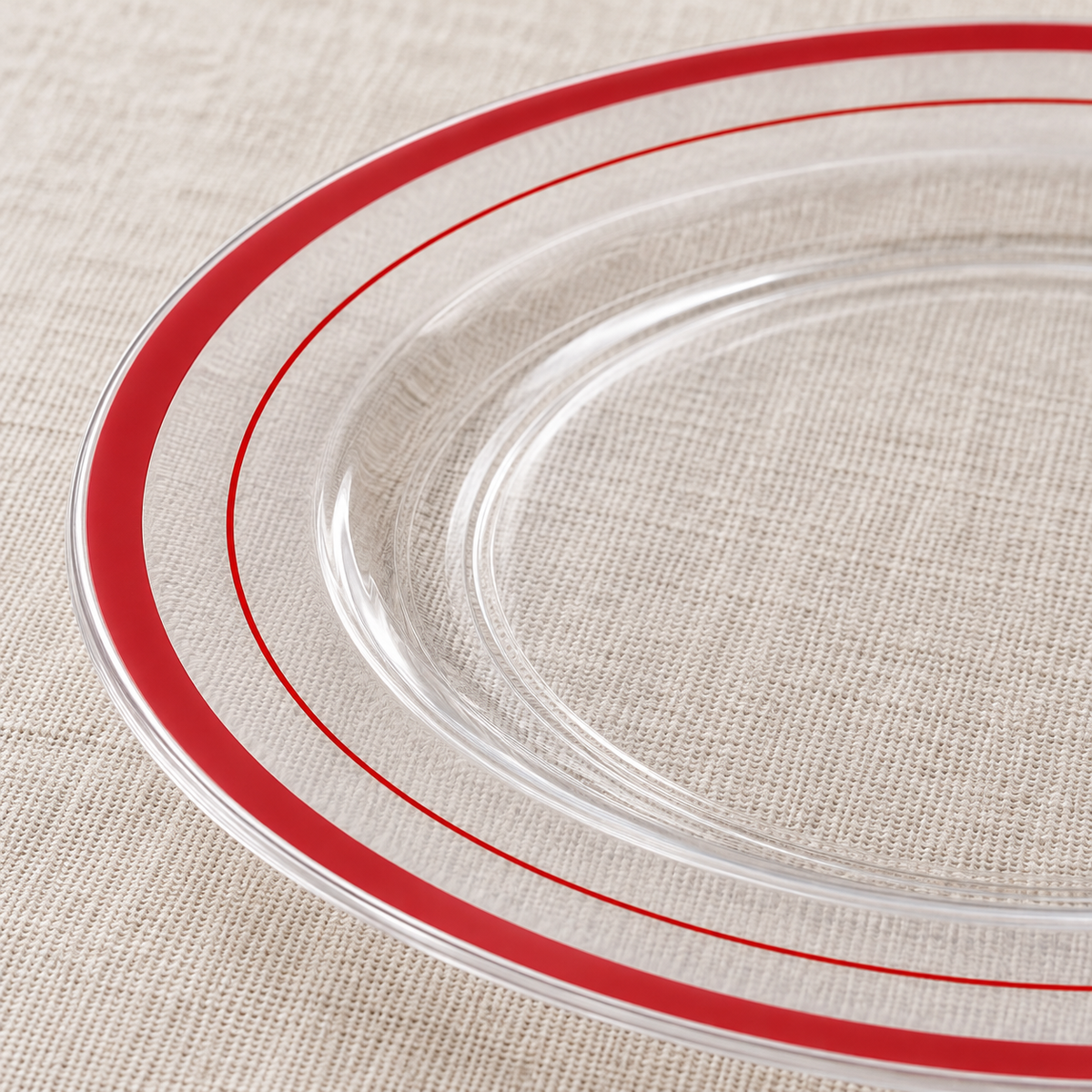 Close-up of clear plastic dessert plates showing the two red rim accents and thin profile. Food, tableware and extra decor are styling props, not included.