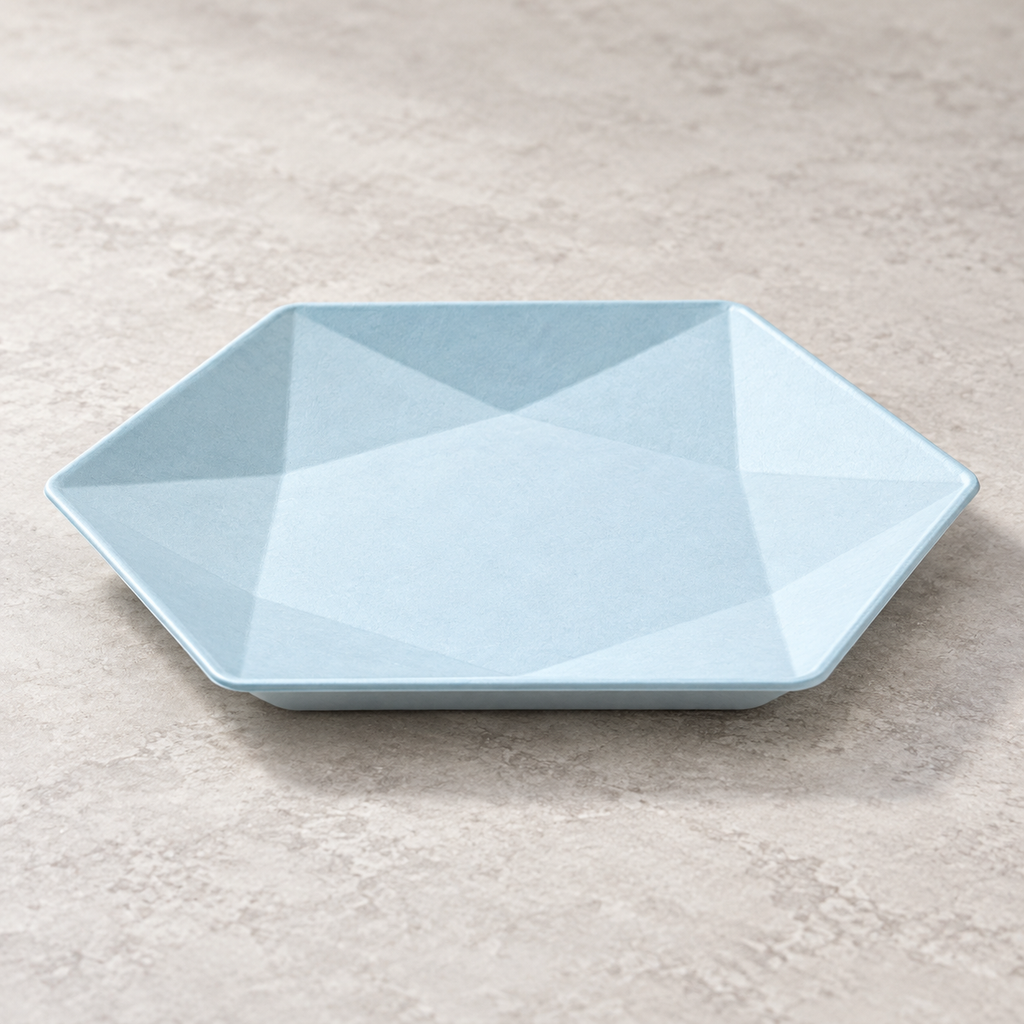 Pale blue hexagonal bagasse plate with triangular facets. Empty angled product view. Representative arrangement, not the full pack quantity.