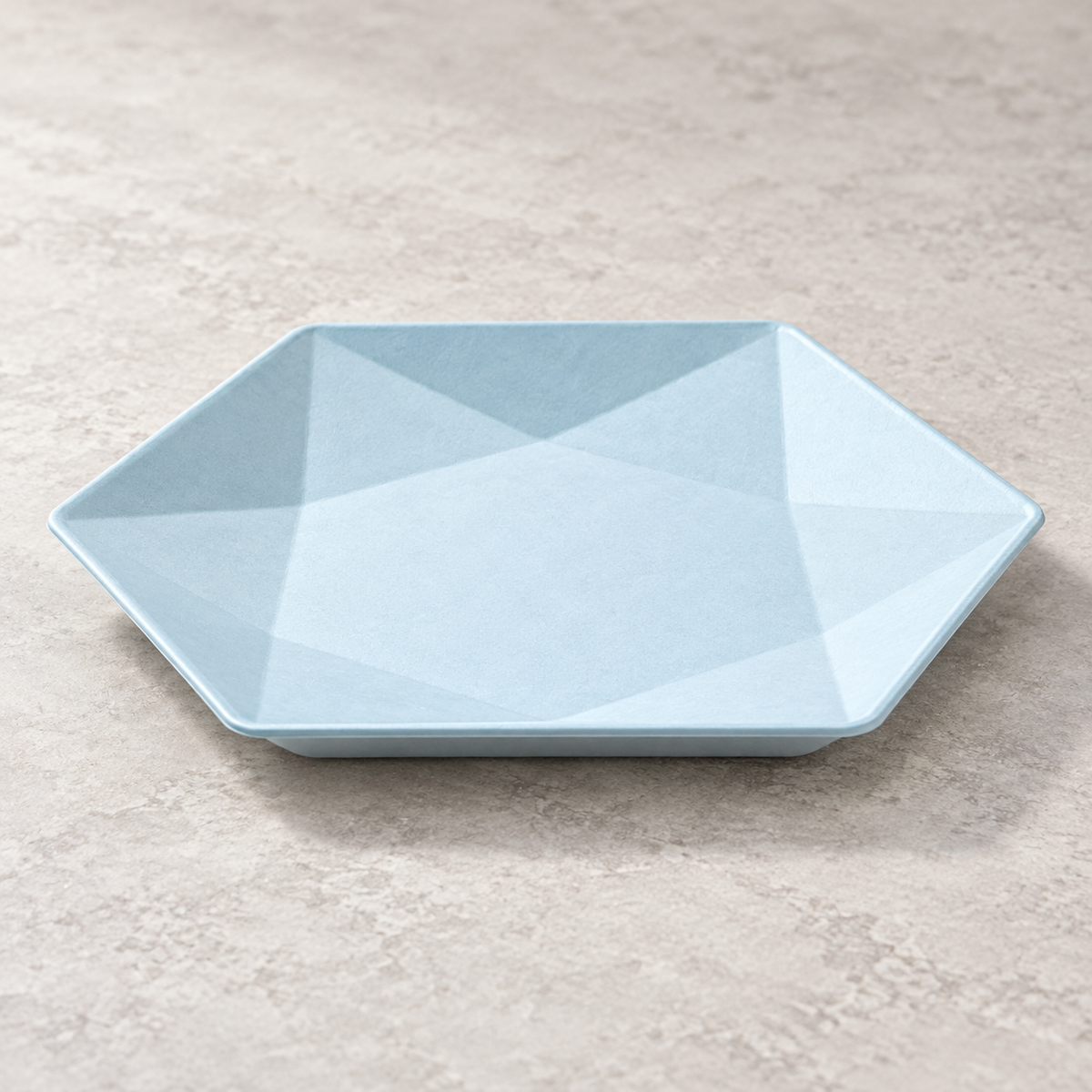 Pale blue hexagonal bagasse plate with triangular facets. Empty angled product view. Representative arrangement, not the full pack quantity.