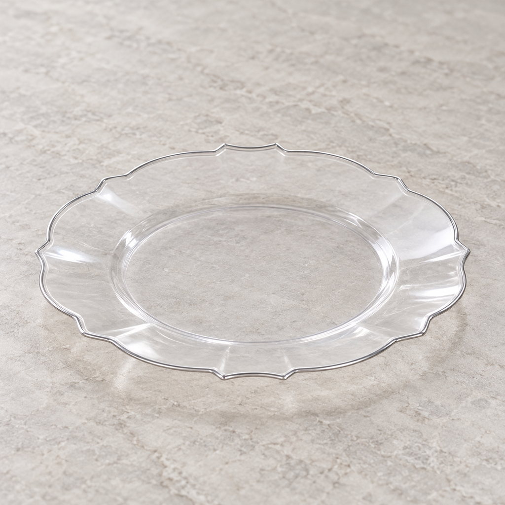 Clear plastic plate with scalloped petal edge and narrow silver rim. Empty angled view showing its shallow profile.