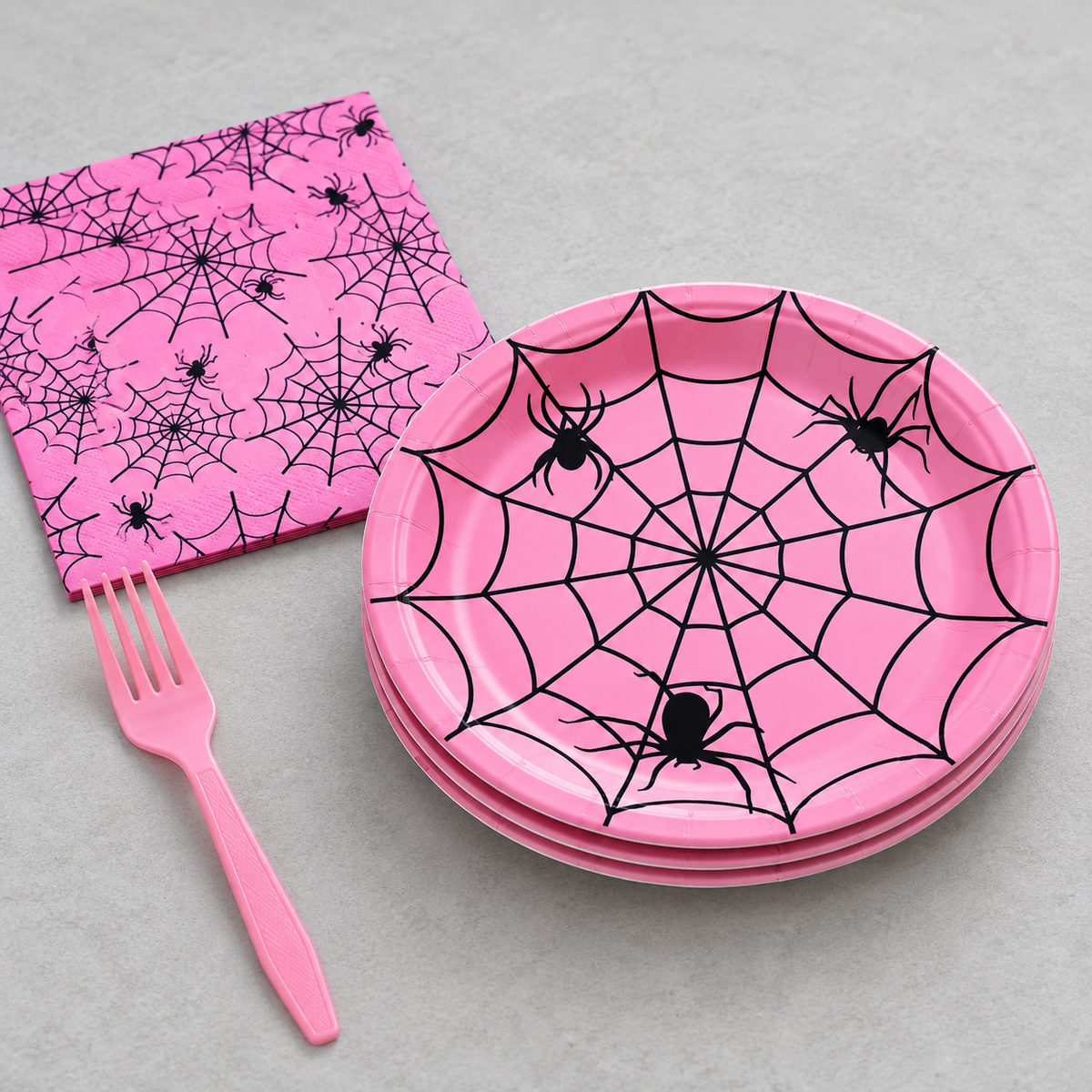 Pink spider-web plates, printed napkin and pink fork. Empty angled product view. Representative arrangement, not the full pack quantity.
