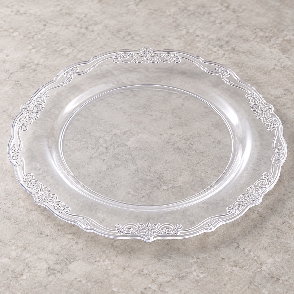 Clear plastic plate with ornate embossed scroll rim. Empty angled view showing its shallow profile.