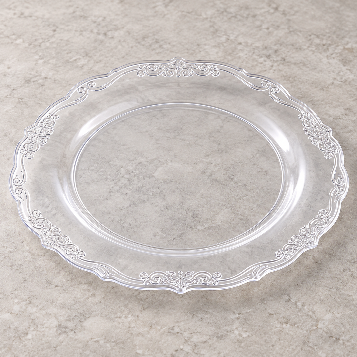 Clear plastic plate with ornate embossed scroll rim. Empty angled view showing its shallow profile.