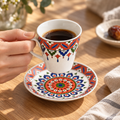 Coral red Turkish coffee cup lifted over its matching saucer