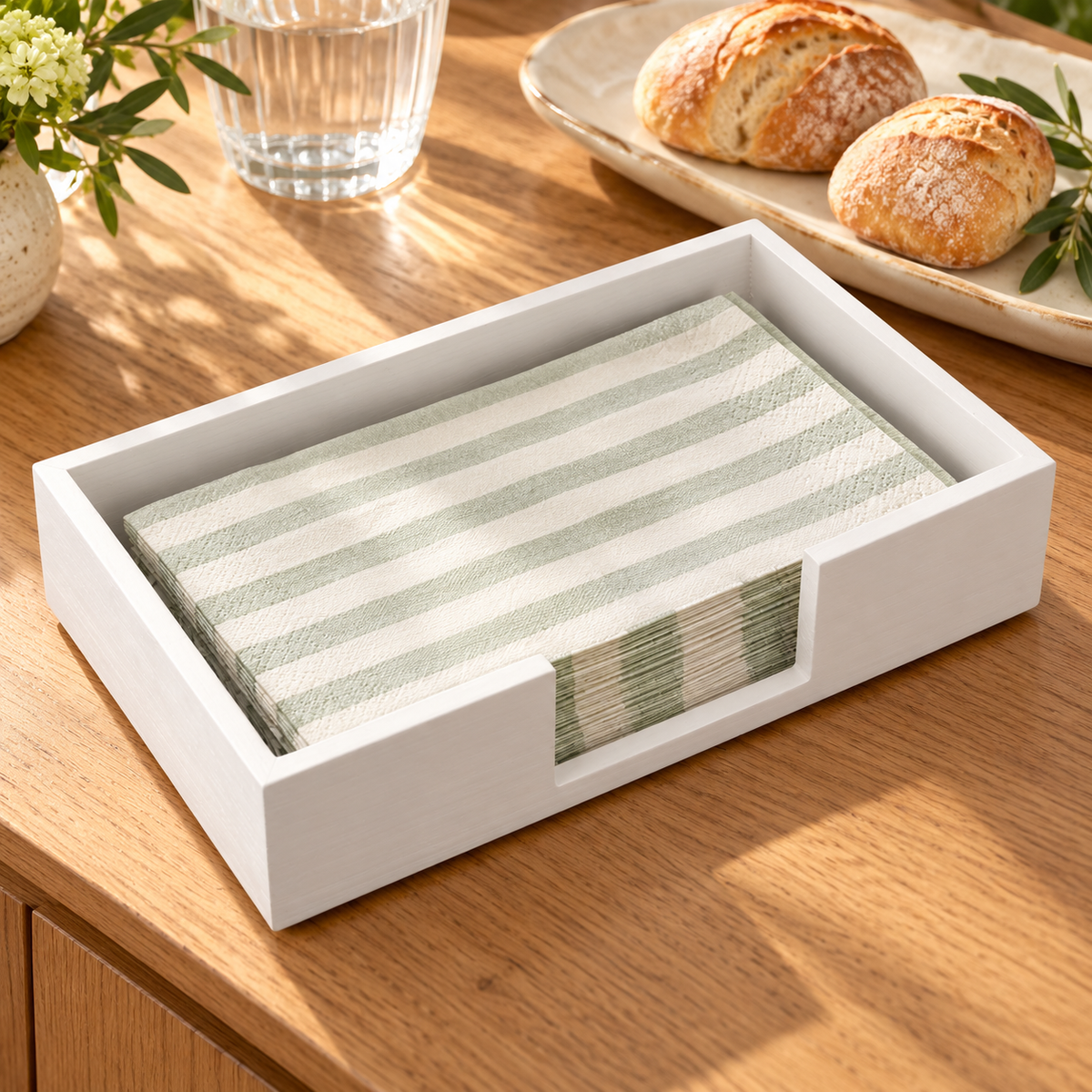 White wooden napkin tray on a buffet sideboard; napkins and tableware are styling props