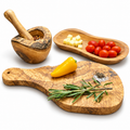 Handled natural-edge wood board, elongated bowl, natural-edge mortar and pestle on white. Food, herbs and spices are styling props, not included.