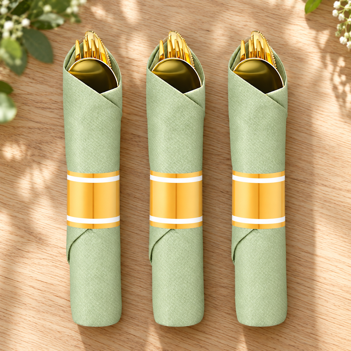 Representative gold-colored plastic cutlery rolls in sage green napkins with gold-and-white bands on a table
