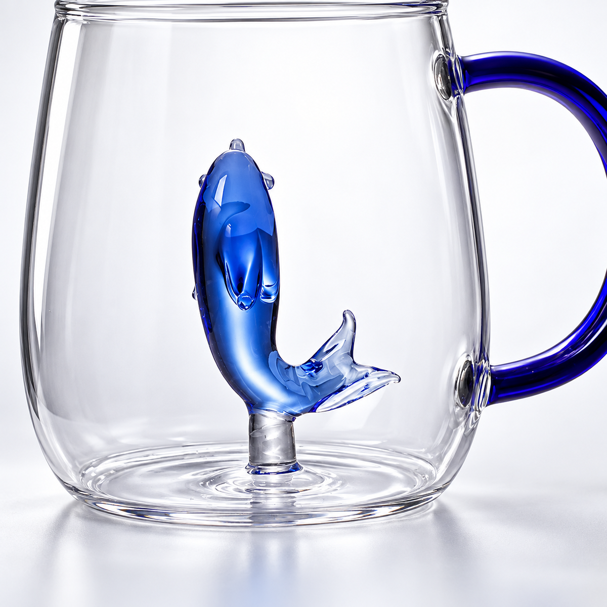 Clear glass mug with cobalt-blue handle and sculpted blue dolphin — detail
