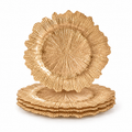 Four gold sunburst glass charger plates on white