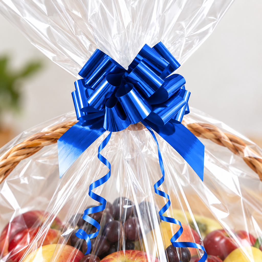 Close detail of the metallic blue multi-loop bow and curling tails on gathered clear film. Basket and fruit are props.