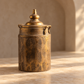 Tall antique-tone decorative lidded urn in a warm indoor setting