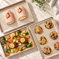 Rectangular gold baking pans with cookies, strawberry rolls and roasted vegetables