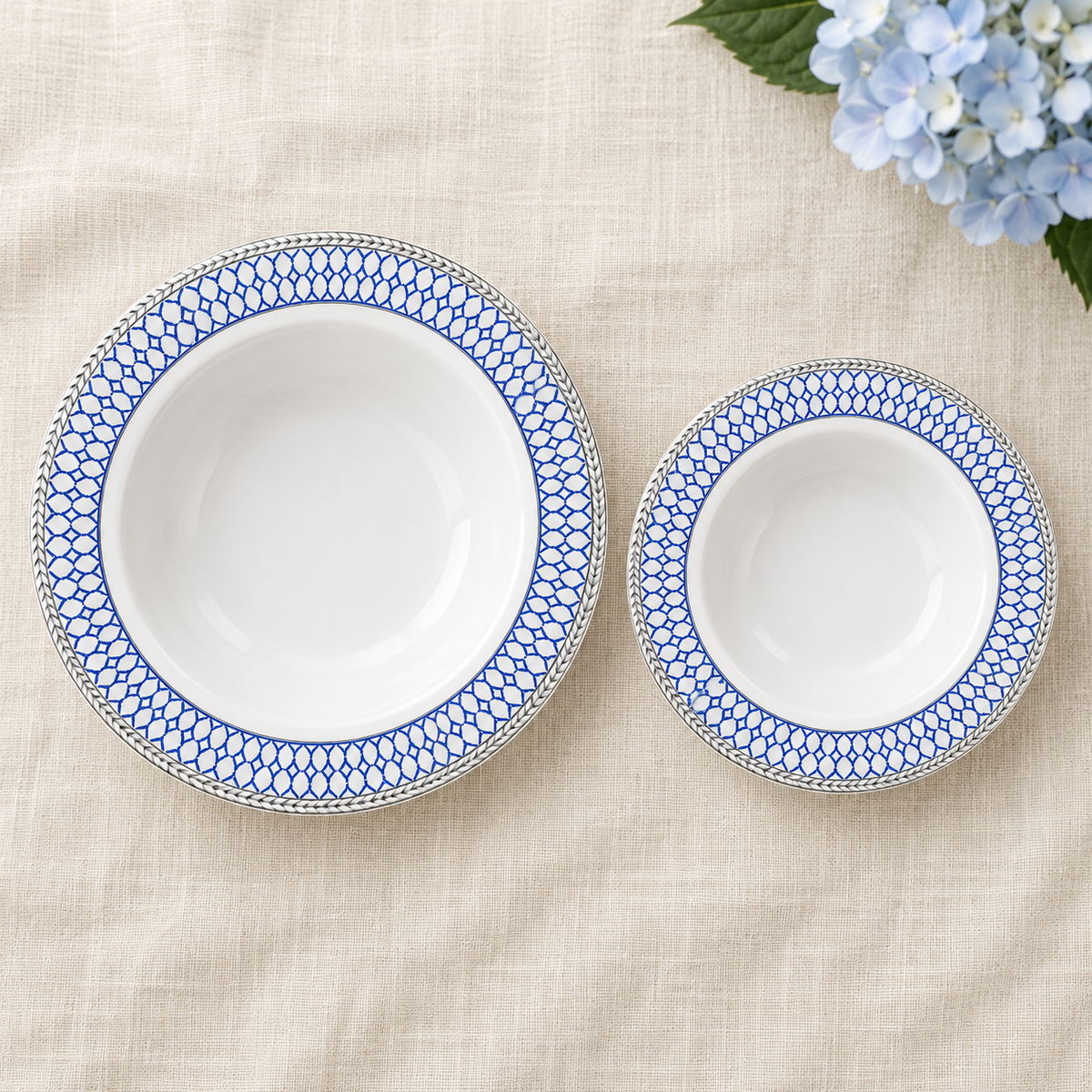Overhead scene showing one soup bowl and one dessert bowl from the blue lattice and silver-rim 32-bowl set; decorative flowers not included