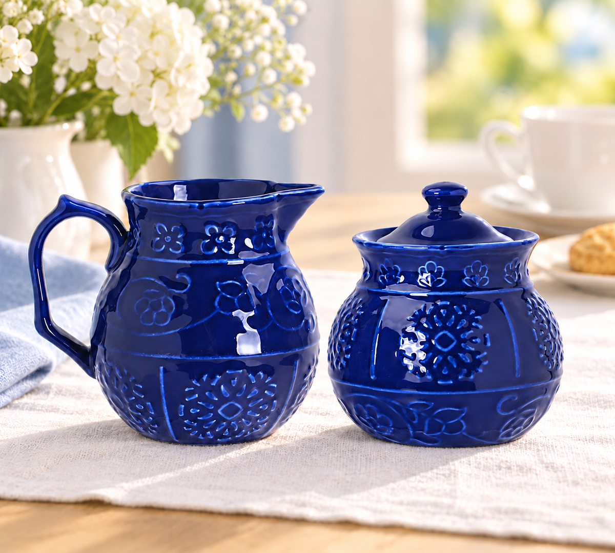Cobalt-blue embossed creamer and closed sugar bowl styled for afternoon tea. Other tableware and flowers are styling props, not included.