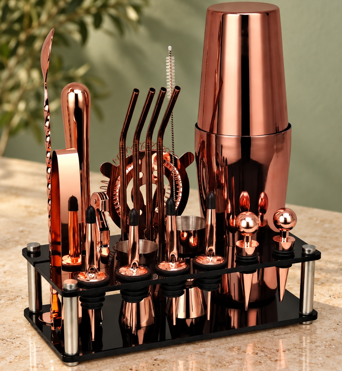 Rose Gold finish Boston cocktail shaker and visible bar tools in black stand on a countertop