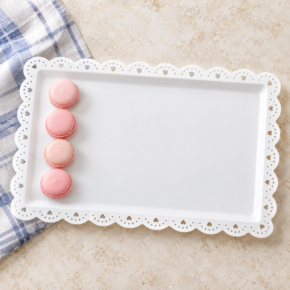 White rectangular appetizer tray with scalloped, heart-and-round perforated rim; macarons and cloth are styling props.