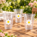 Three clear cups with white daisy prints on a garden party table; styled partial display.