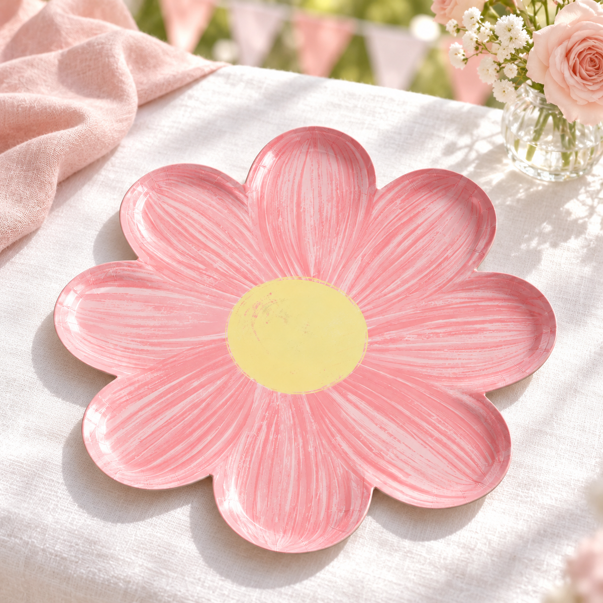Light pink flower paper plate styled on a pink-and-white celebration table. Styling props and food are not included.
