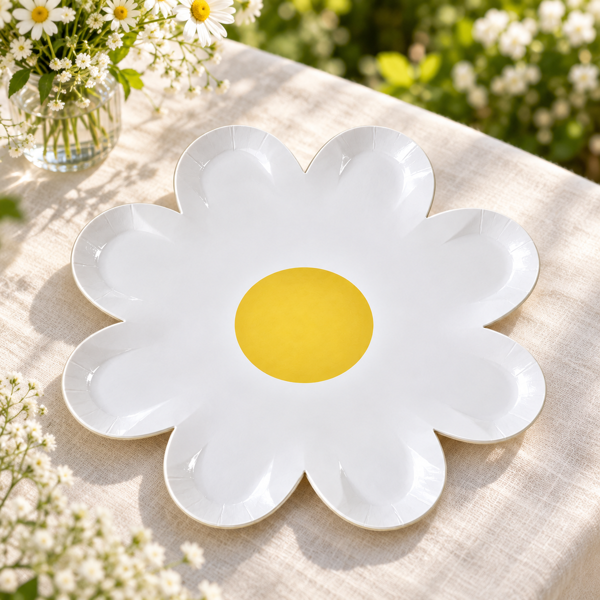 White eight-petal flower paper plate on a linen garden-party table. Styling props and food are not included.