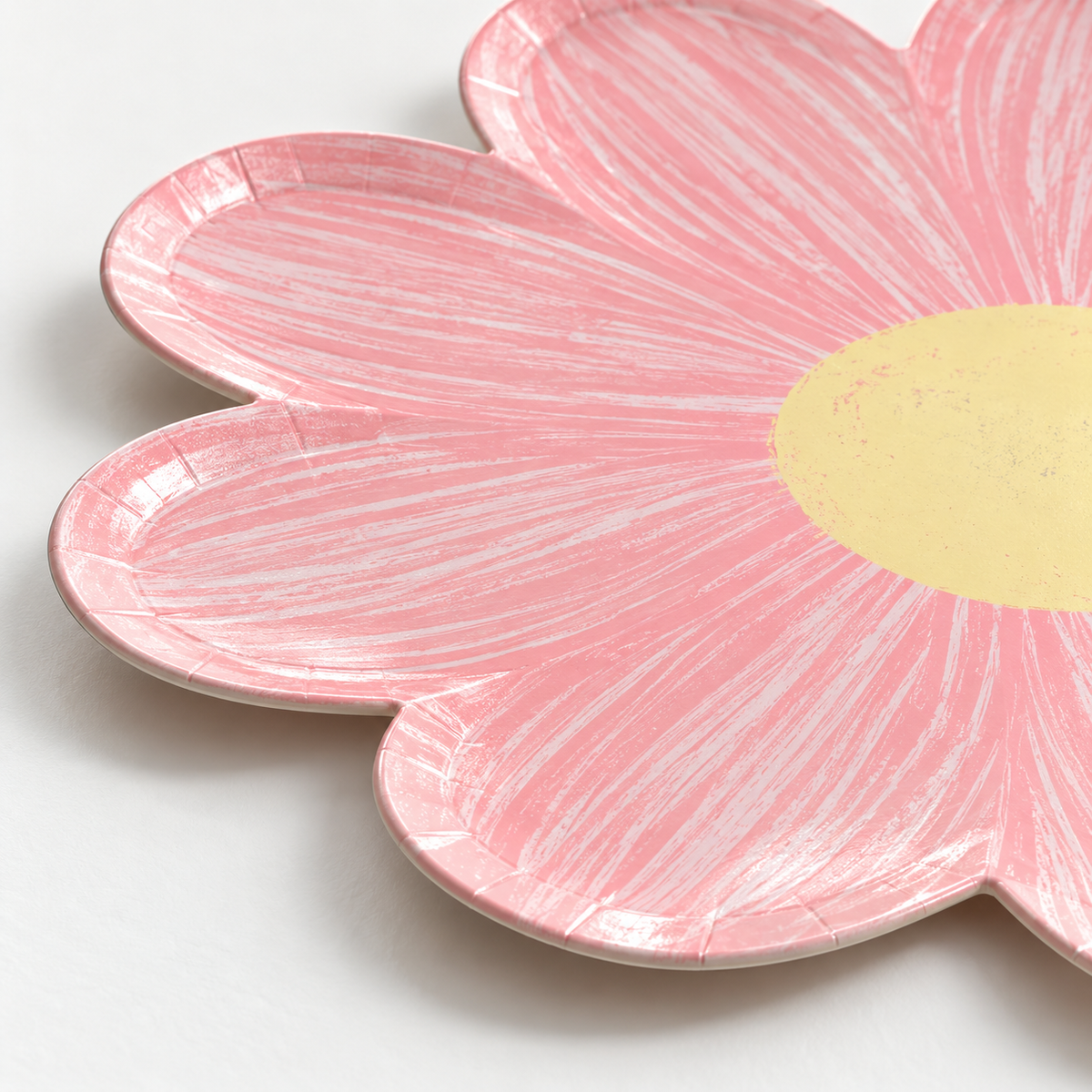 Close-up of light pink printed petals, yellow center and thin creased paper rim.