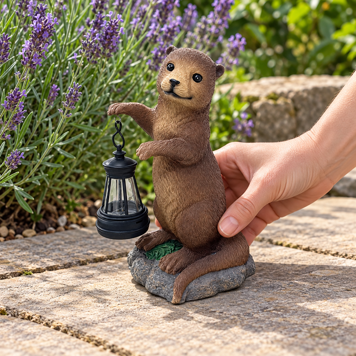 Hand placing the small otter statue on garden paving