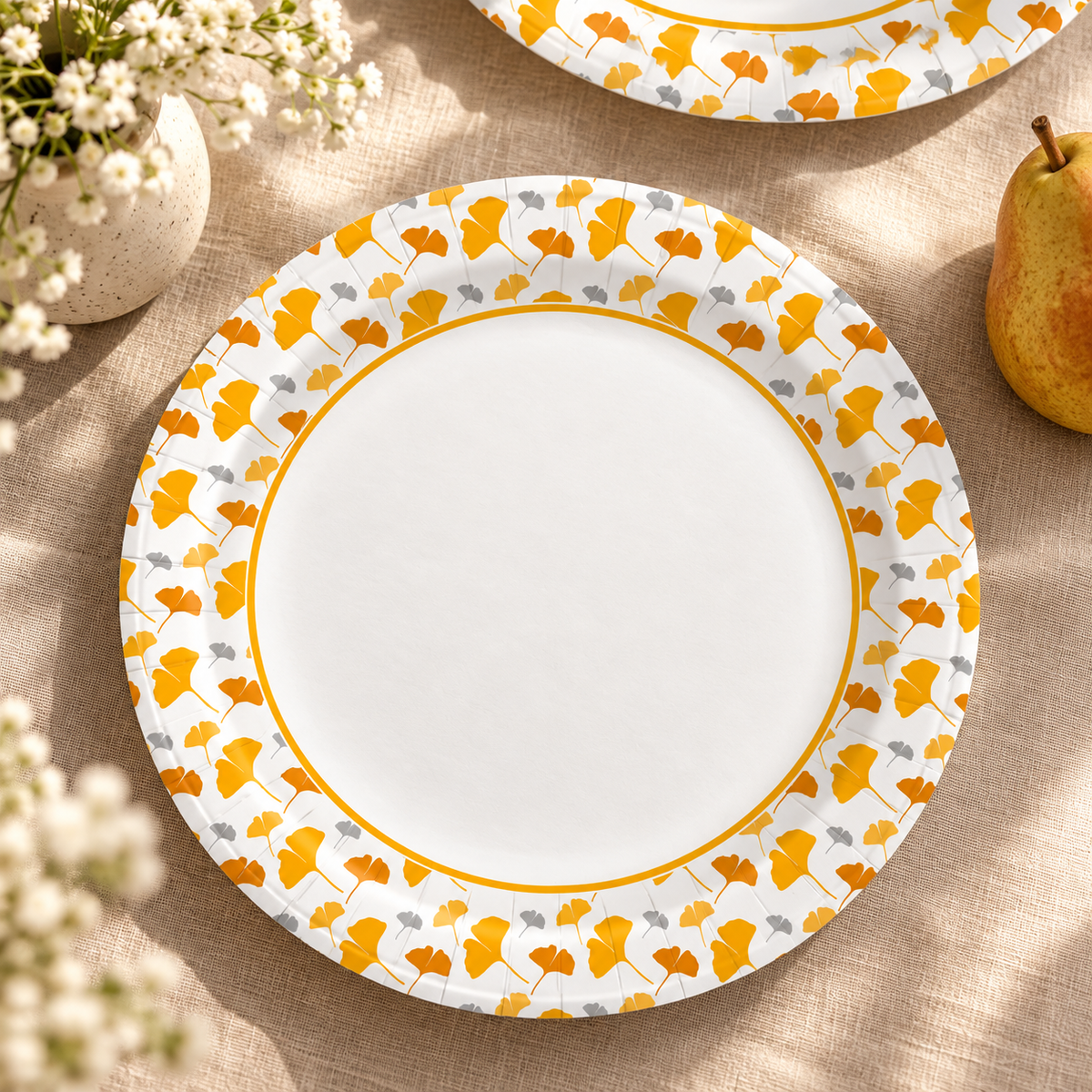 Representative ginkgo-pattern paper plate on a linen table; pear and flowers are styling props, not included.