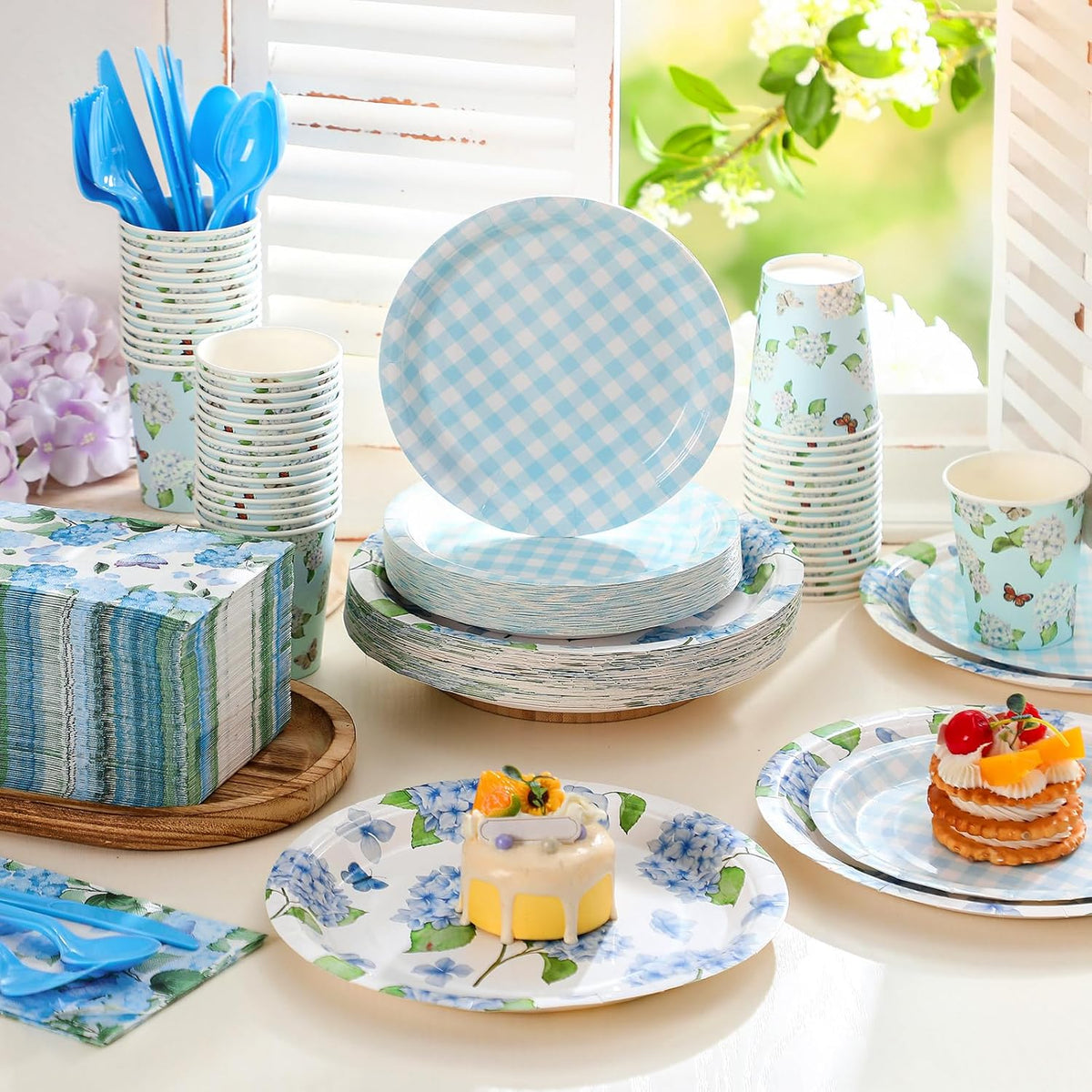 Blue hydrangea and gingham party tableware arranged for a garden party; food and decor not included