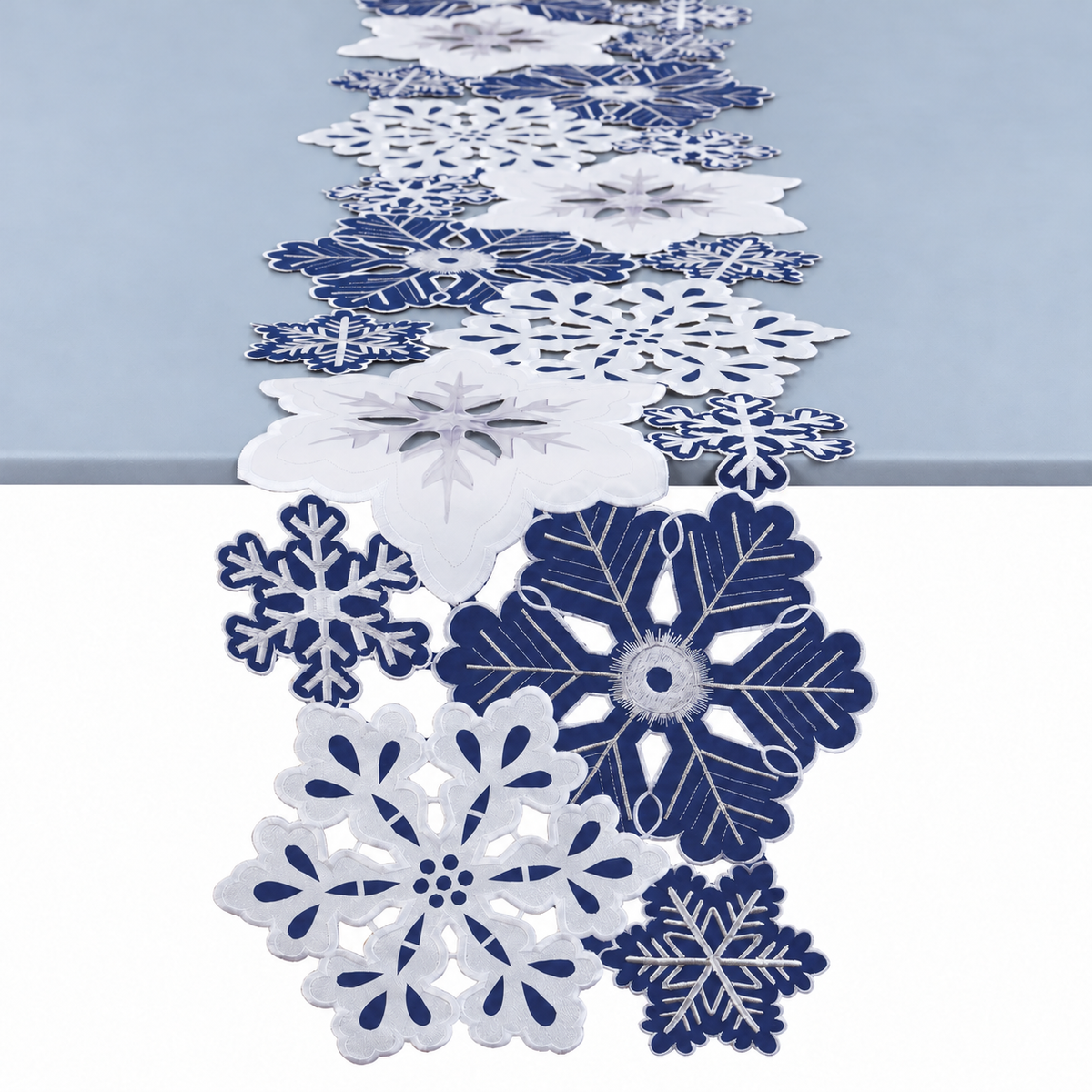 Snowflake runner draped over a pale blue-grey table edge, showing embroidered motifs and cutwork