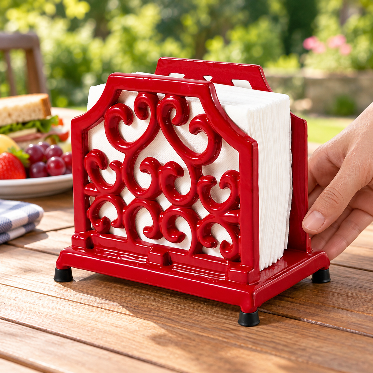 Hand setting the red napkin stand on a picnic table; napkins and props not included.