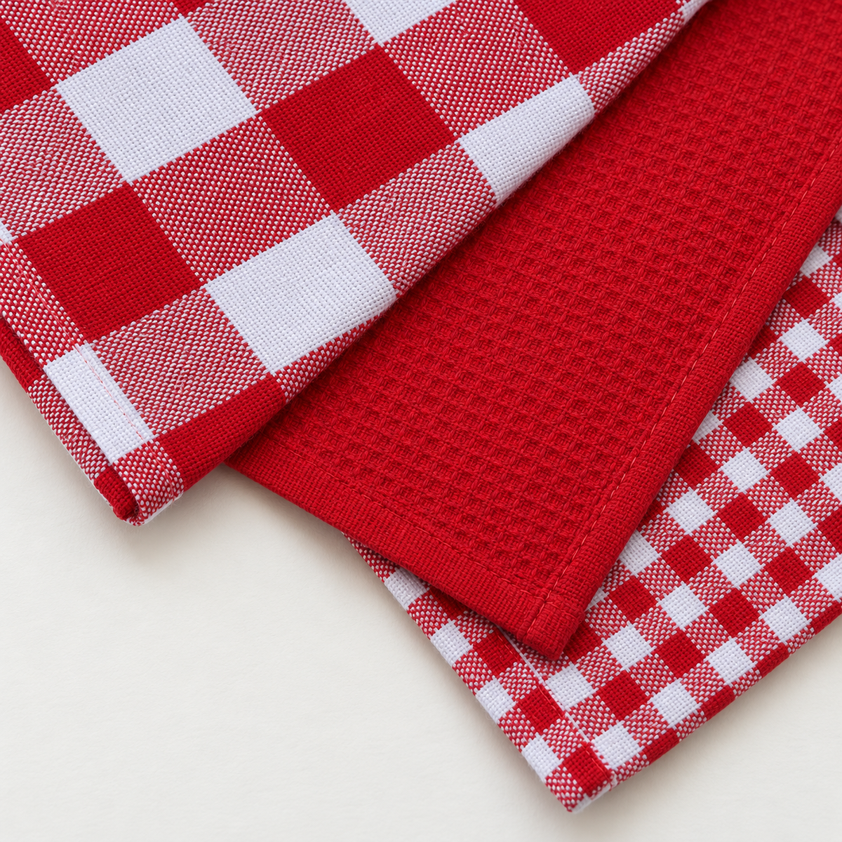 Close view of the large-check, solid-red, and small-check towel fabrics and stitched hems.