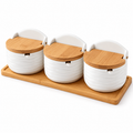 Exact three-jar white wavy ceramic seasoning set with closed wood lids on wood tray, white background