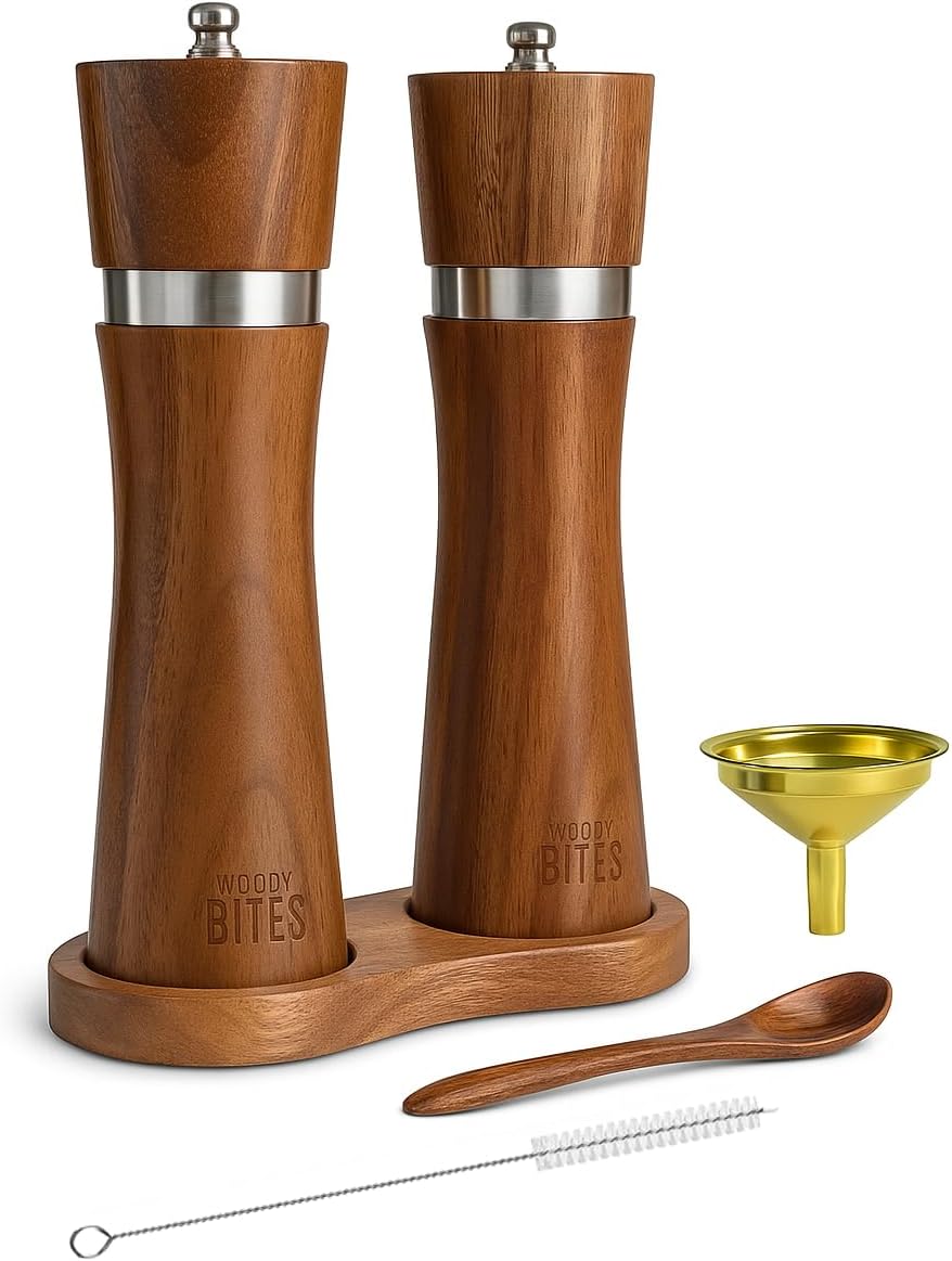 Two WOODYBITES acacia wood mills on their wooden base with the included gold-tone funnel, wooden spoon and cleaning brush.