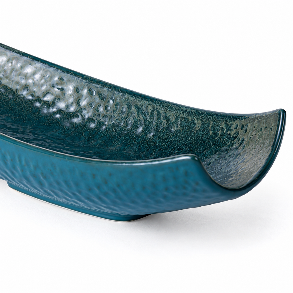 Close-up of the curved rim and textured glaze of the peacock-green serving vessel
