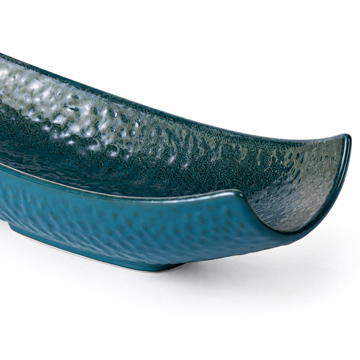 Close-up of the curved rim and textured glaze of the peacock-green serving vessel