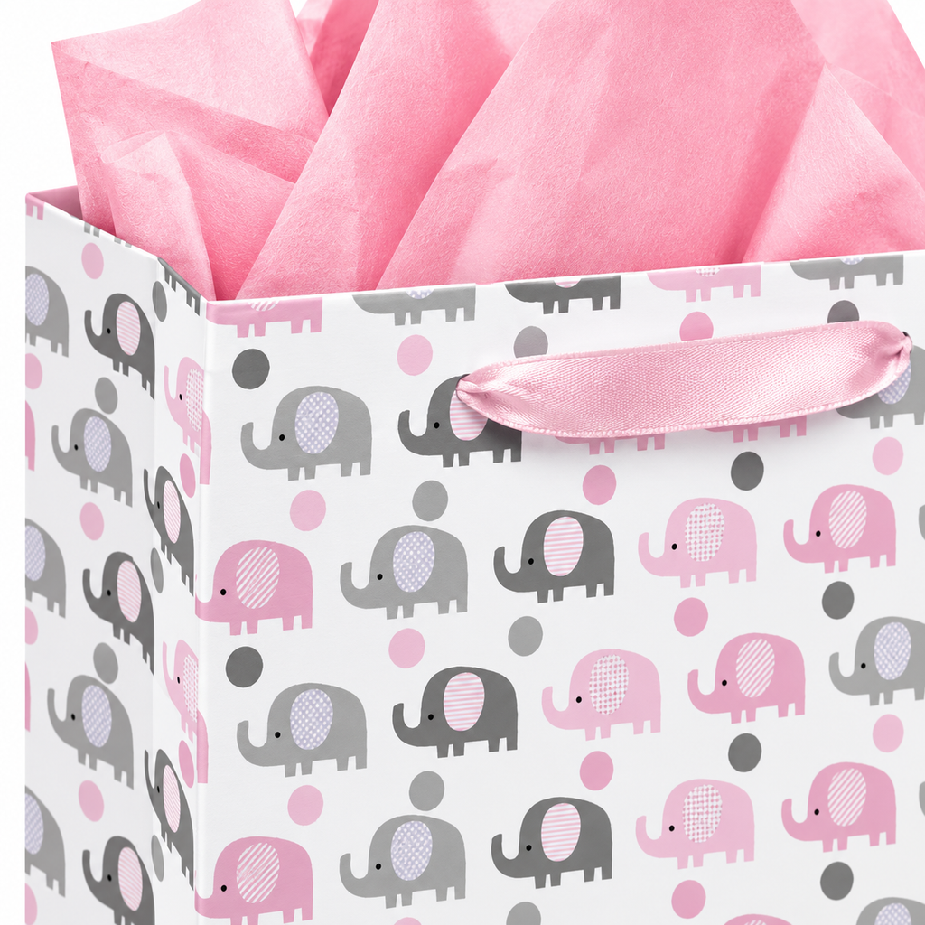 Close-up of pink satin ribbon handle, elephant print, folded paper corner and pink tissue
